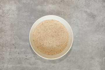 Top view of psyllium husks flakes in a white bowl.