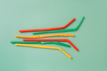 Crumpled plastic straws on a green background.