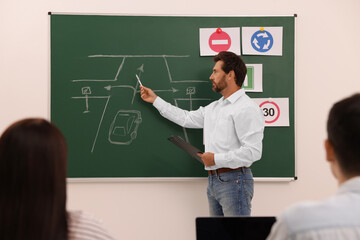 Teacher explaining traffic rules to audience during lesson in driving school