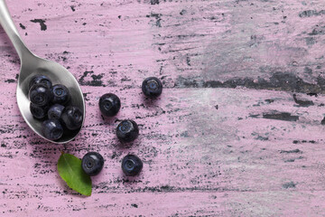 Ripe bilberries and leaf on wooden rustic table, flat lay. Space for text