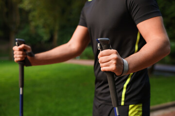 Man practicing Nordic walking with poles outdoors, closeup