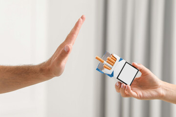 Stop smoking concept. Man refusing cigarettes on blurred background, closeup