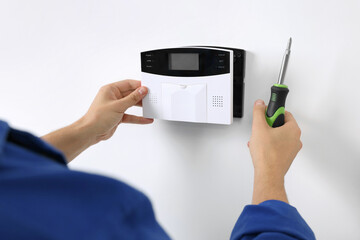 Man installing home security alarm system on white wall indoors, closeup - obrazy, fototapety, plakaty