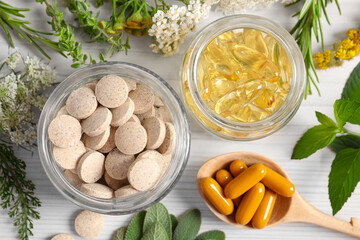 Different pills, flowers and herbs on white wooden table, flat lay. Dietary supplements