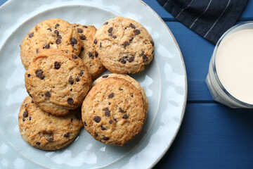 Tasty chocolate chip cookies and glass of milk on blue wooden table, flat lay
