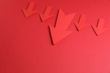 Many paper arrows on red background, above view. Space for text