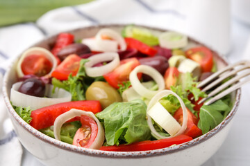 Bowl of tasty salad with leek and olives on table, closeup