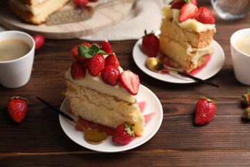 Tasty cake with fresh strawberries, mint and cups of drink on wooden table