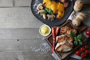 Delicious grilled meat and vegetables served on wooden table, flat lay. Space for text