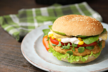 Tasty vegan burger with vegetables, patty and microgreens on wooden table, closeup. Space for text