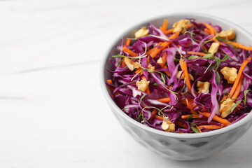Fototapeta na wymiar Tasty salad with red cabbage and walnuts on white wooden table, closeup. Space for text