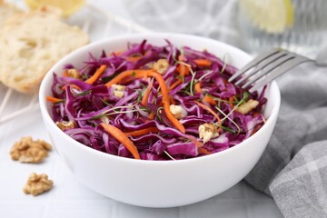 Tasty salad with red cabbage and walnuts on white tiled table, closeup