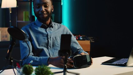 Tech content creator filming technology review of newly released gaming VR glasses for audience in home studio. BIPOC influencer showing virtual reality headset to subscribers