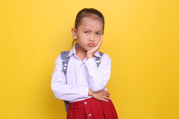 Beautiful Asian little girl in elementary school uniform sulking and thinking
