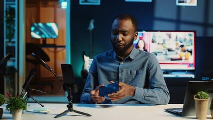 Technology content creator filming review of newly released smartphone, unboxing it and giving feedback about touchscreen to audience. Online star endorsing sponsor branded cellphone to subscribers