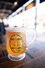 Fototapeta premium JAPAN - NOV 13, 2023: Delicious BUTTERBEER craft drink alcohol free with honey bee vintage label on a glass in Warner Bros. Studio Tour Tokyo, The Making of Harry Potter