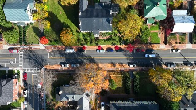 American town in autumn. Aerial top down truck shot of houses and homes lining street with colorful fall tree foliage. Northeast USA small town.