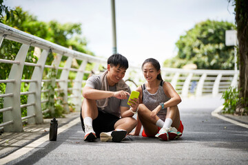 young asian couple using cellphone outdoors
