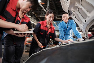 Asian male professional automotive supervisor advises and inspects a mechanic worker woman about...