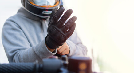 Cropped image of biker putting on leather gloves to drive his motorbike.