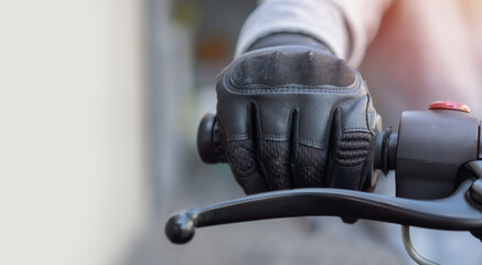 Hand of a man in protective motorcycle gloves holds a black motorcycle