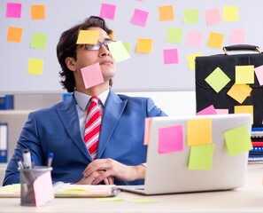 Young male handsome employee in conflicting priorities concept