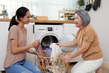 senior woman and young woman doing laundry with washing machine at home
