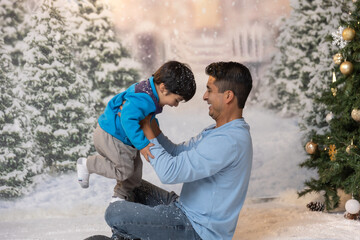 Latino father happily holding his son at Christmas time