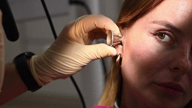otolaryngologist conducts medical examination of ear with otoscope closeup