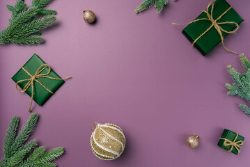 Christmas flat lay on a purple background with fir branch, balls and box