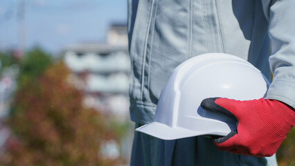 ヘルメットを持つ作業服の男性｜建設業・製造業などのイメージ