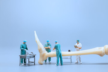 Miniature people , Anatomy model of the human ankle joint with a doctor on a blue backdrop