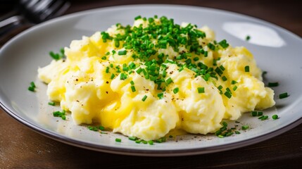 an image of a plate of fluffy scrambled eggs with chives and grated cheese