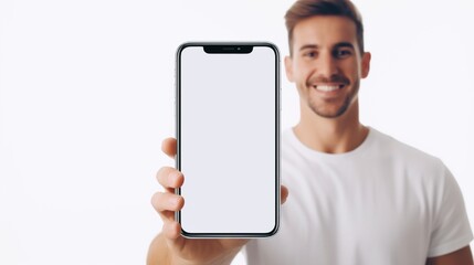 Fototapeta na wymiar A cheerful young man wearing casual attire displays his smartphone while grinning. White screen mockup of a phone.