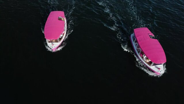 aerial view of two pink boats driving beside each other in the ocean