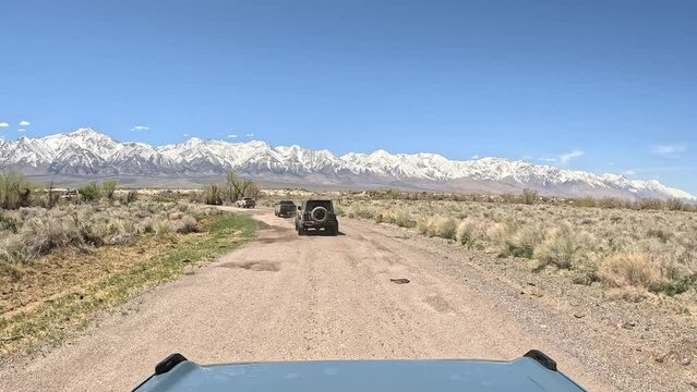 Convoy of overland enthusiasts driving along a dirt trail in California's Alabama Hills - driver point of view