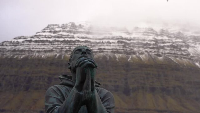 Praying man sculptures. Stunning frozen mountain in the background. Cinematic shot.