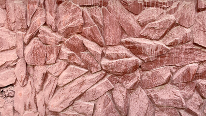 Beautiful red stone wall of different sizes. The texture of masonry.