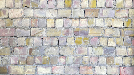A wall of multicolored bricks of different sizes. The construction texture of an old dilapidated brick.