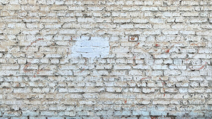 An old brick wall. A fragment of a dilapidated fence. White shabby brickwork.