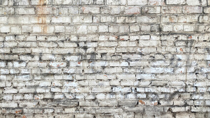 The brick wall of an old dilapidated building. The background is made of white shabby brickwork.