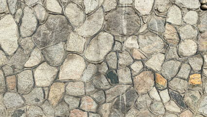 A wall of stones of different sizes and colors. Beautiful texture of stone masonry with veins.
