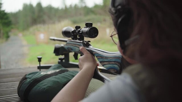 Practice and patience as young woman fires at distant target, handheld
