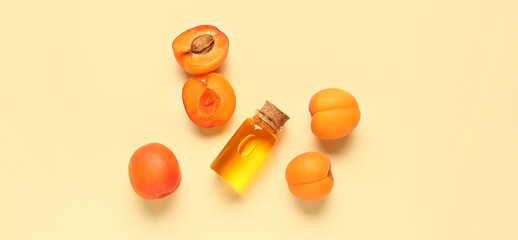Bottle of essential oil and ripe apricots on beige background