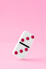 Domino piece on pink background close up