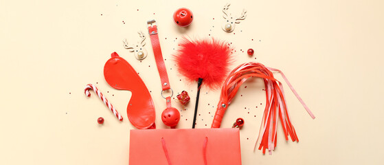 Shopping bag, sex toys and Christmas decorations on beige background