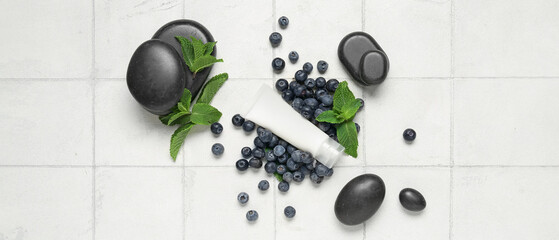 Cosmetic product, spa stones, blueberry and mint leaves on light tile background