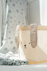 Fototapeta na wymiar Rabbit basket for toys and blanket in baby bed