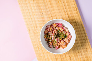The photo is a plate of food on a wooden plank, with a bowl on the table and a wall and floor in the background. The food is tagged as a legume.
