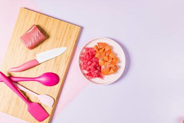 A plate of food on a cutting board next to a knife and spoon.A plate of raw fish and tuna.
A knife on a cutting board.
A cutting board with pink utensils and a spoon.
